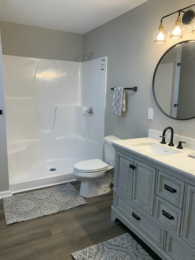 bathroom featuring walk in shower, vanity, toilet, and hardwood / wood-style floors