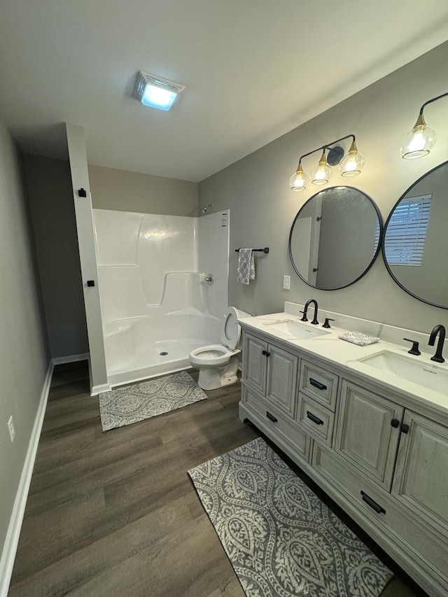 bathroom with vanity, toilet, hardwood / wood-style floors, and a shower