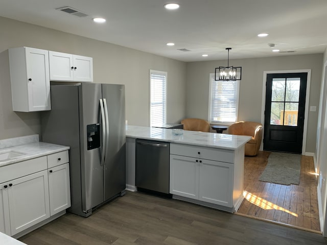 kitchen with appliances with stainless steel finishes, dark hardwood / wood-style flooring, kitchen peninsula, and white cabinets