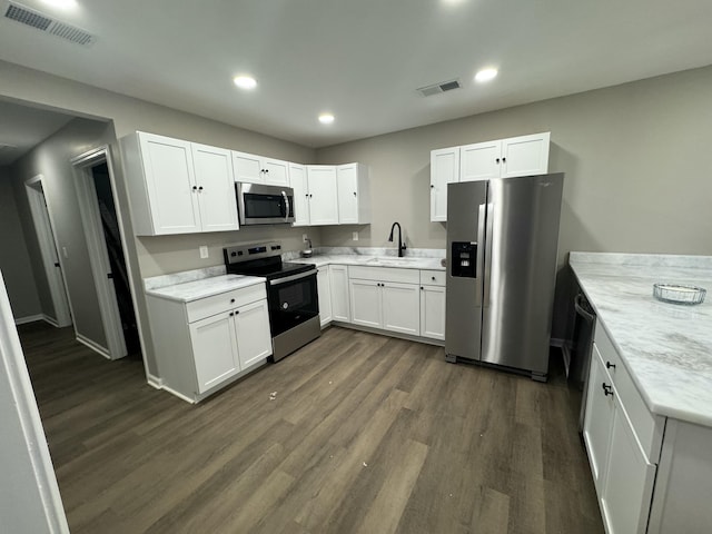 kitchen with dark wood-type flooring, sink, white cabinetry, stainless steel appliances, and light stone countertops