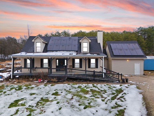 view of front of property featuring solar panels and a porch