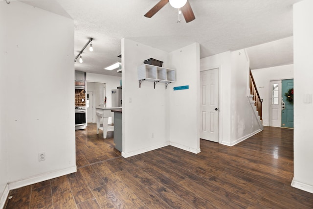 unfurnished room with a textured ceiling, ceiling fan, rail lighting, and dark hardwood / wood-style floors