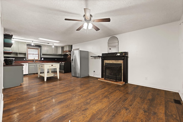 kitchen featuring a textured ceiling, stainless steel appliances, a fireplace, sink, and dark hardwood / wood-style floors