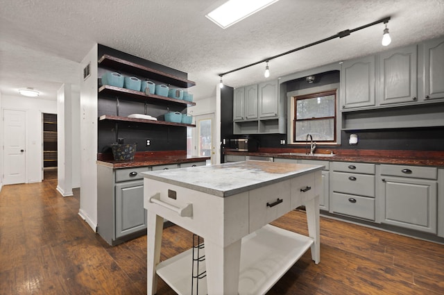 kitchen with a textured ceiling, a center island, sink, gray cabinetry, and a breakfast bar area