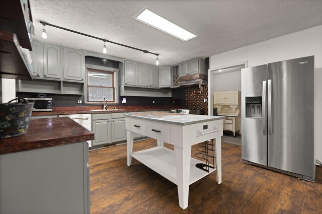 kitchen with stainless steel fridge, dark hardwood / wood-style floors, track lighting, a textured ceiling, and sink