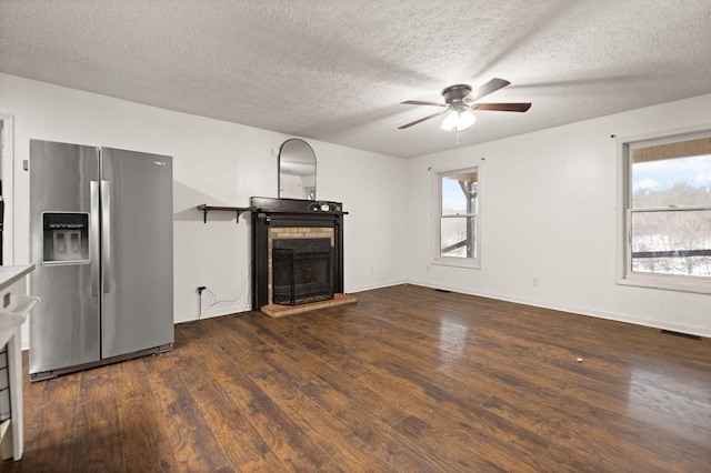 unfurnished living room featuring a healthy amount of sunlight, dark hardwood / wood-style flooring, and a textured ceiling