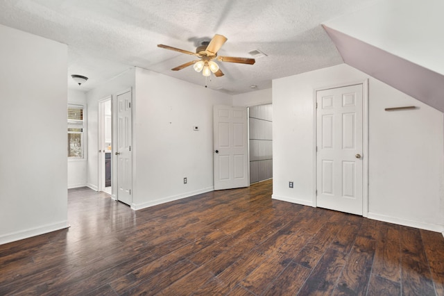 bonus room with ceiling fan, vaulted ceiling, dark wood-type flooring, and a textured ceiling