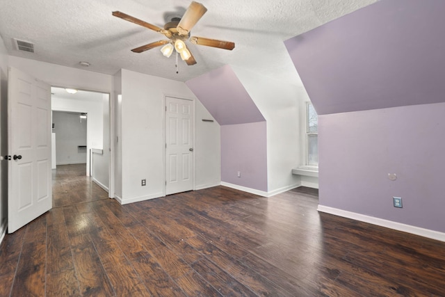 additional living space with ceiling fan, dark wood-type flooring, a textured ceiling, and vaulted ceiling