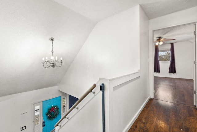 stairway with vaulted ceiling, a textured ceiling, ceiling fan with notable chandelier, and hardwood / wood-style flooring