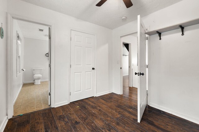 unfurnished bedroom featuring a textured ceiling, dark hardwood / wood-style floors, a closet, ceiling fan, and ensuite bathroom