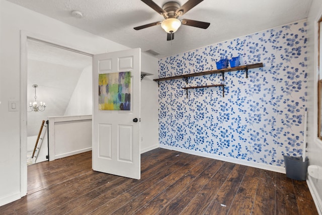 empty room with a textured ceiling, dark hardwood / wood-style flooring, and ceiling fan with notable chandelier