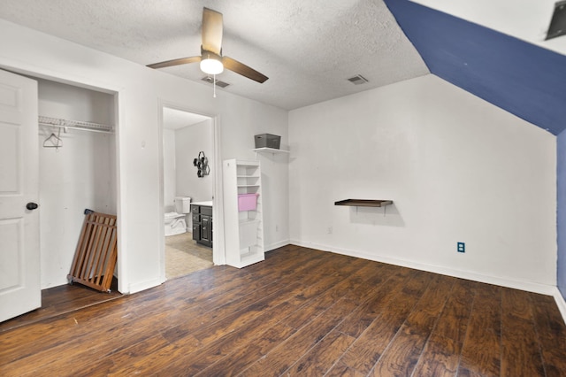 unfurnished bedroom with ceiling fan, dark wood-type flooring, a textured ceiling, and a closet