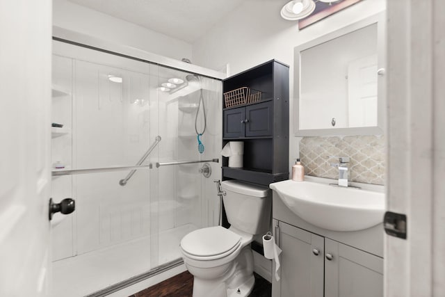 bathroom featuring toilet, vanity, backsplash, and a shower with door