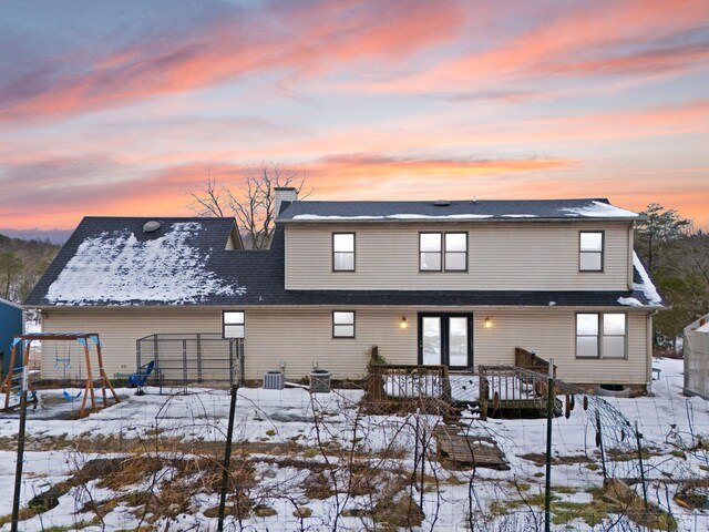 snow covered rear of property with central AC and a wooden deck