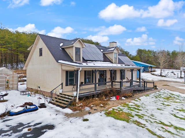 view of front of house with solar panels, an outbuilding, and a porch