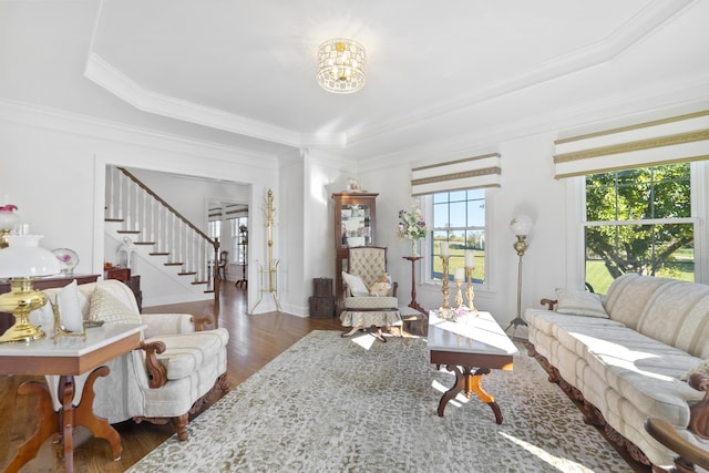 living room with a tray ceiling, dark hardwood / wood-style floors, ornamental molding, and an inviting chandelier