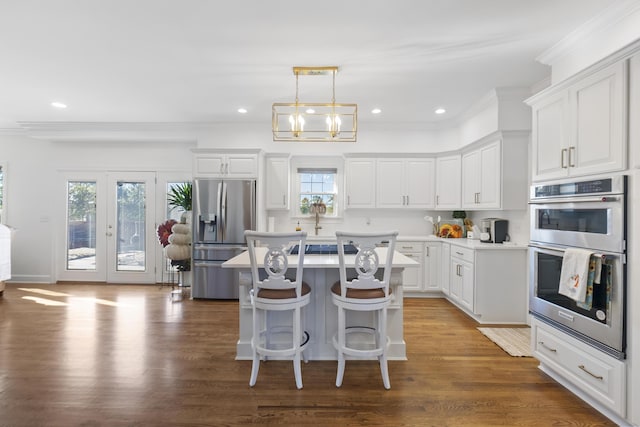 kitchen featuring a center island, white cabinetry, hanging light fixtures, appliances with stainless steel finishes, and plenty of natural light