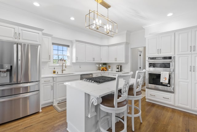 kitchen featuring appliances with stainless steel finishes, sink, light stone countertops, white cabinets, and a center island