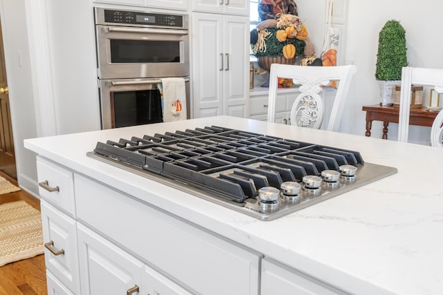 room details with hardwood / wood-style floors, stainless steel appliances, and white cabinetry