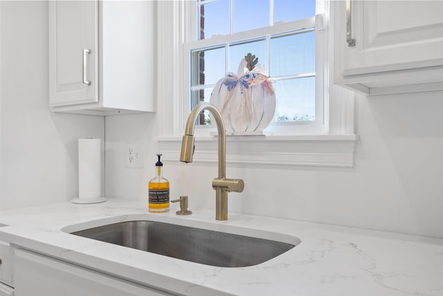 details featuring light stone counters, sink, and white cabinets