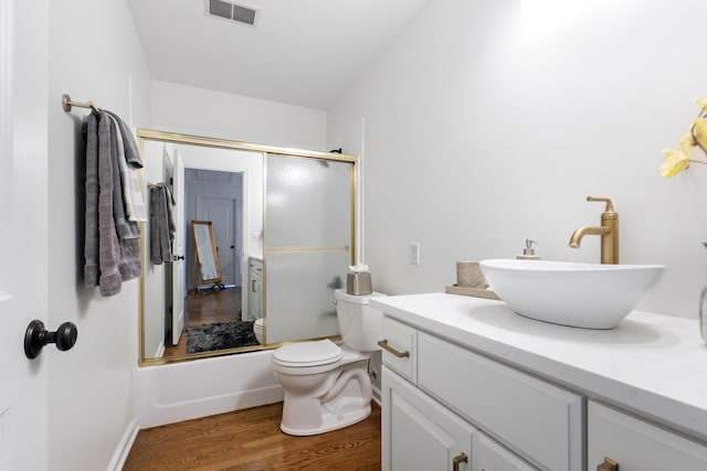 full bathroom featuring toilet, vanity, shower / bath combination with glass door, and hardwood / wood-style flooring