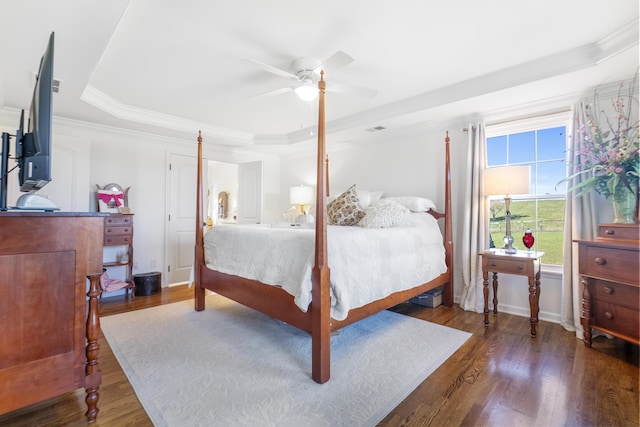 bedroom with ceiling fan, a tray ceiling, dark hardwood / wood-style floors, and crown molding