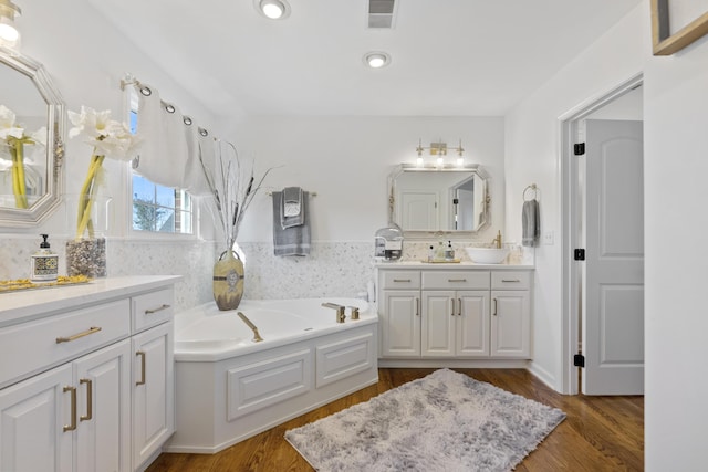 bathroom featuring vanity, decorative backsplash, a bathing tub, and hardwood / wood-style flooring