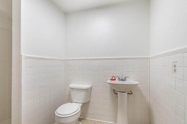 bathroom with tile walls and toilet