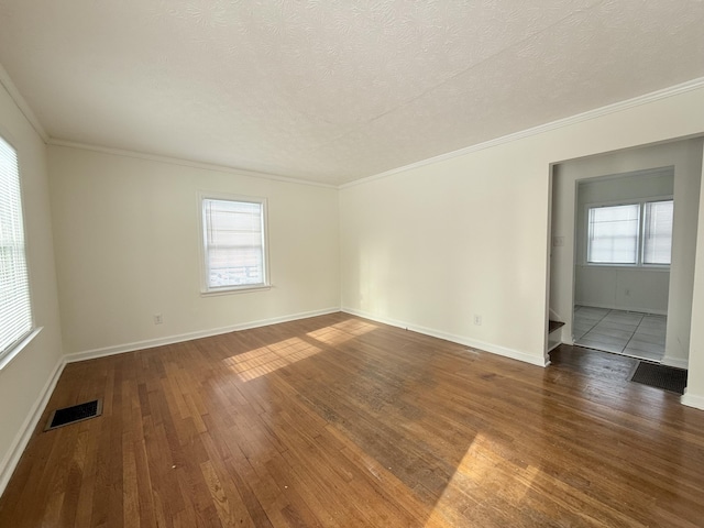 spare room featuring dark hardwood / wood-style flooring, crown molding, and a textured ceiling