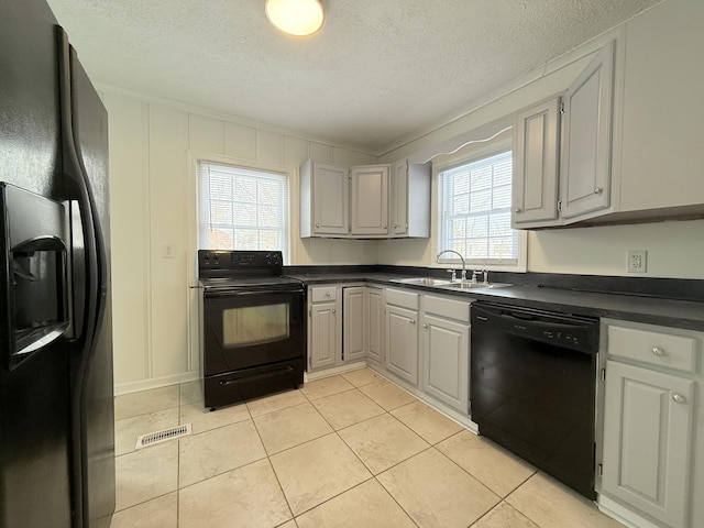 kitchen with sink, light tile patterned floors, gray cabinetry, black appliances, and a textured ceiling