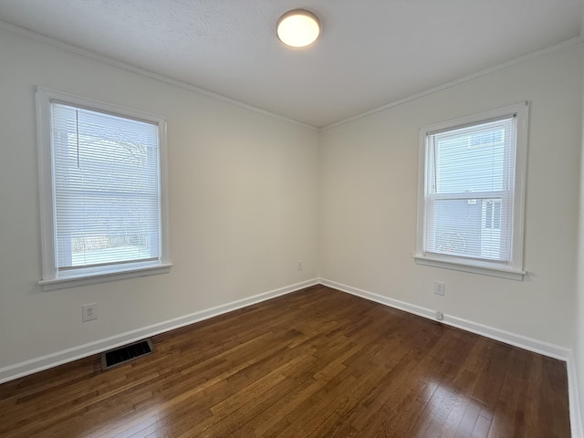 spare room with crown molding, plenty of natural light, and dark wood-type flooring