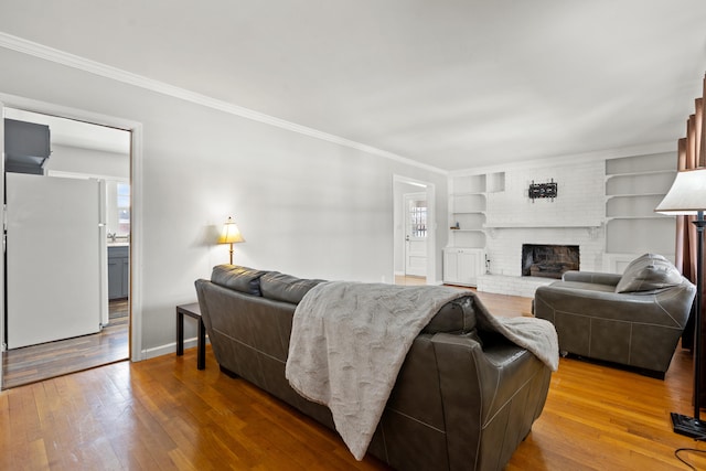 living room featuring hardwood / wood-style flooring, ornamental molding, a fireplace, and built in features