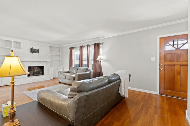 living room featuring crown molding, a brick fireplace, hardwood / wood-style flooring, and built in features