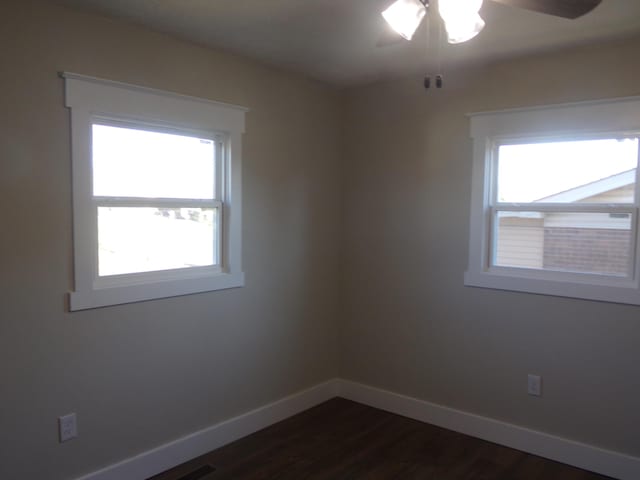 unfurnished room featuring dark wood-style flooring, ceiling fan, and baseboards