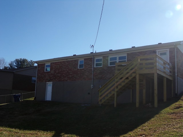 rear view of house with stairs, fence, a lawn, and brick siding