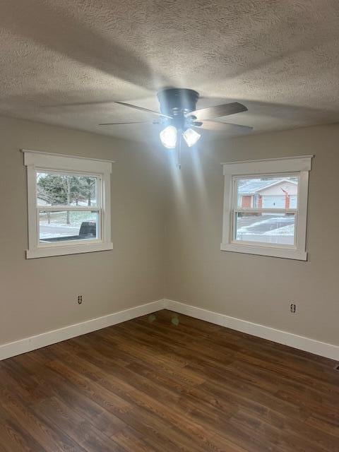 spare room featuring a textured ceiling, dark wood-style flooring, a ceiling fan, and baseboards