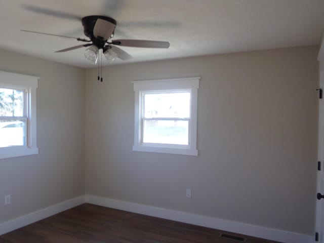 unfurnished room with dark wood-style flooring, visible vents, ceiling fan, and baseboards