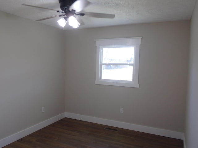 empty room featuring baseboards, visible vents, ceiling fan, dark wood-style flooring, and a textured ceiling