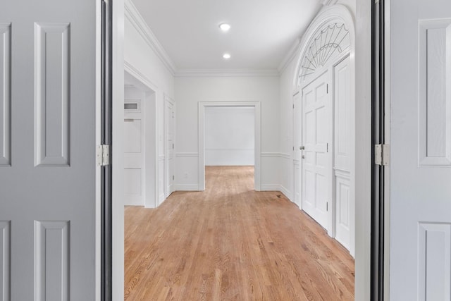 hall with ornamental molding and light wood-type flooring