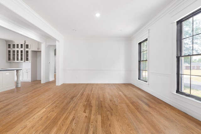 spare room with plenty of natural light, ornamental molding, and light wood-type flooring