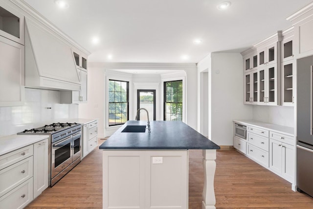 kitchen featuring sink, a center island with sink, white cabinetry, and stainless steel appliances