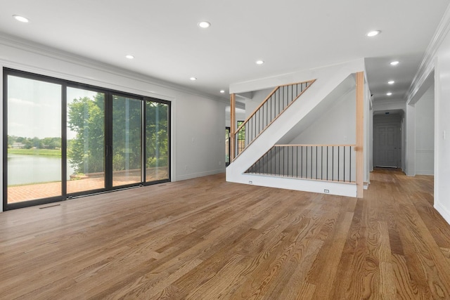 unfurnished living room featuring ornamental molding and light wood-type flooring