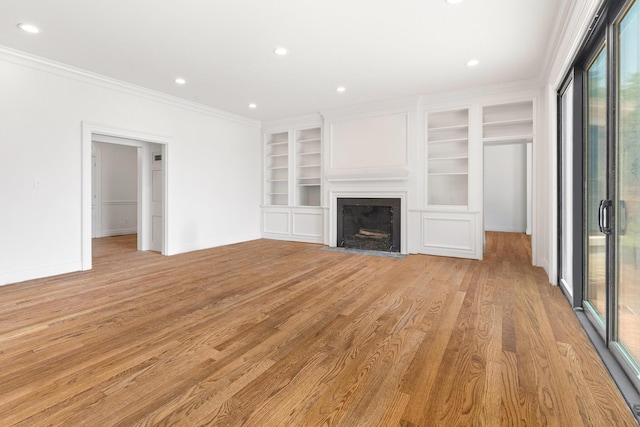 unfurnished living room featuring built in shelves, ornamental molding, and light hardwood / wood-style floors