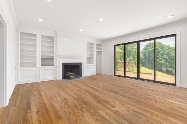 unfurnished living room with light hardwood / wood-style floors, built in features, and crown molding