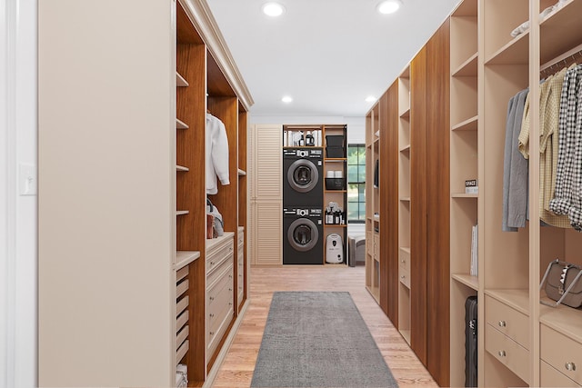 spacious closet featuring light hardwood / wood-style flooring and stacked washer and dryer