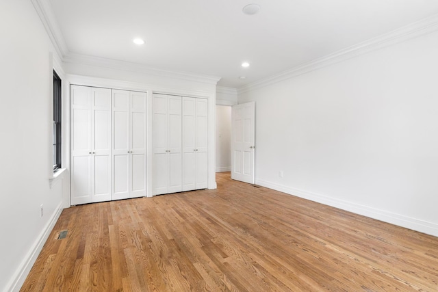 unfurnished bedroom featuring multiple closets, light hardwood / wood-style flooring, and ornamental molding