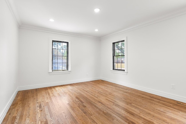 empty room featuring light hardwood / wood-style flooring, a wealth of natural light, and crown molding