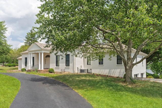 neoclassical home with cooling unit and a front lawn