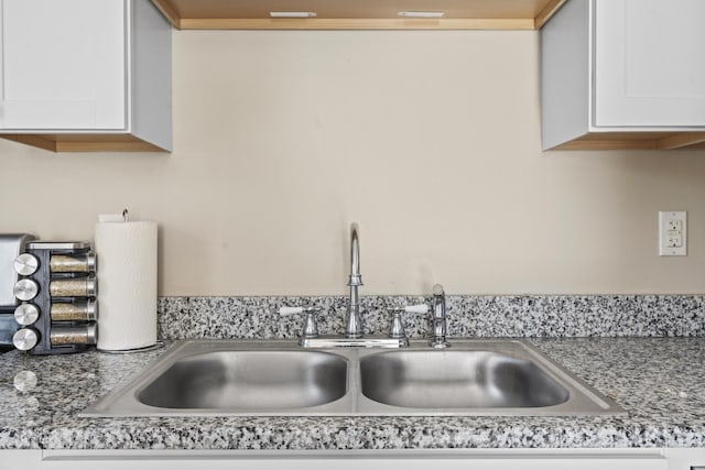 details with sink, white cabinetry, and light stone countertops