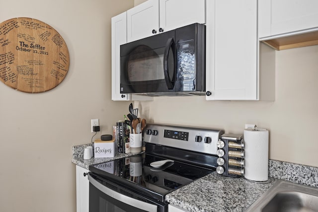 kitchen featuring white cabinetry, light stone counters, and electric range